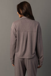A person with long brown hair is shown from the back, wearing the Gray Cropped Washed Soft Button Up from Panache Apparel Collection, standing against a plain gray background.