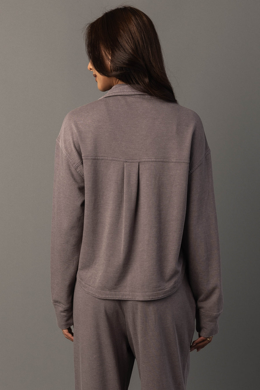 A person with long brown hair is shown from the back, wearing the Gray Cropped Washed Soft Button Up from Panache Apparel Collection, standing against a plain gray background.