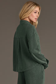 A person wearing a Pine Green Cropped Washed Soft Button Up, featuring a long-sleeved cropped design in a soft washed fabric.