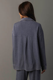 A person with long brown hair is standing with their back to the camera, wearing the Panache Apparel Collection Slate Blue Washed Soft Button Up and matching pants against a plain gray background.