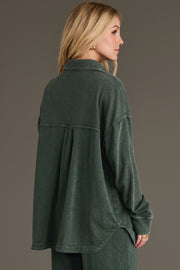 A person wearing a Pine Green Washed Soft Button Up, a pine green, soft washed button-up shirt with a relaxed fit and a pleated back detail.