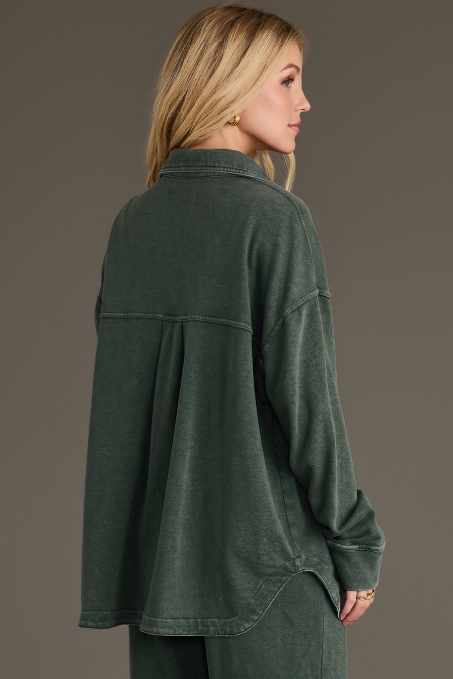 A person wearing a Pine Green Washed Soft Button Up, a pine green, soft washed button-up shirt with a relaxed fit and a pleated back detail.
