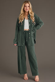 A woman wearing a Pine Green Washed Soft Button Up over a white ribbed crop top, paired with matching wide-leg lounge pants in a relaxed fit.