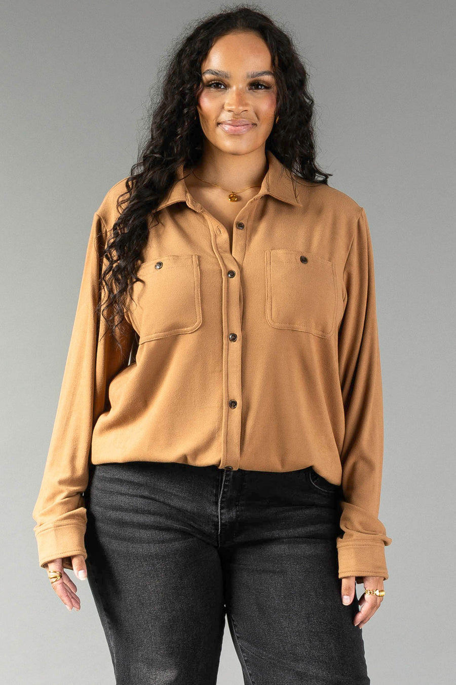 A person wears a Dark Tan Super Soft Button Up, featuring long sleeves, two chest pockets, and dark jeans.