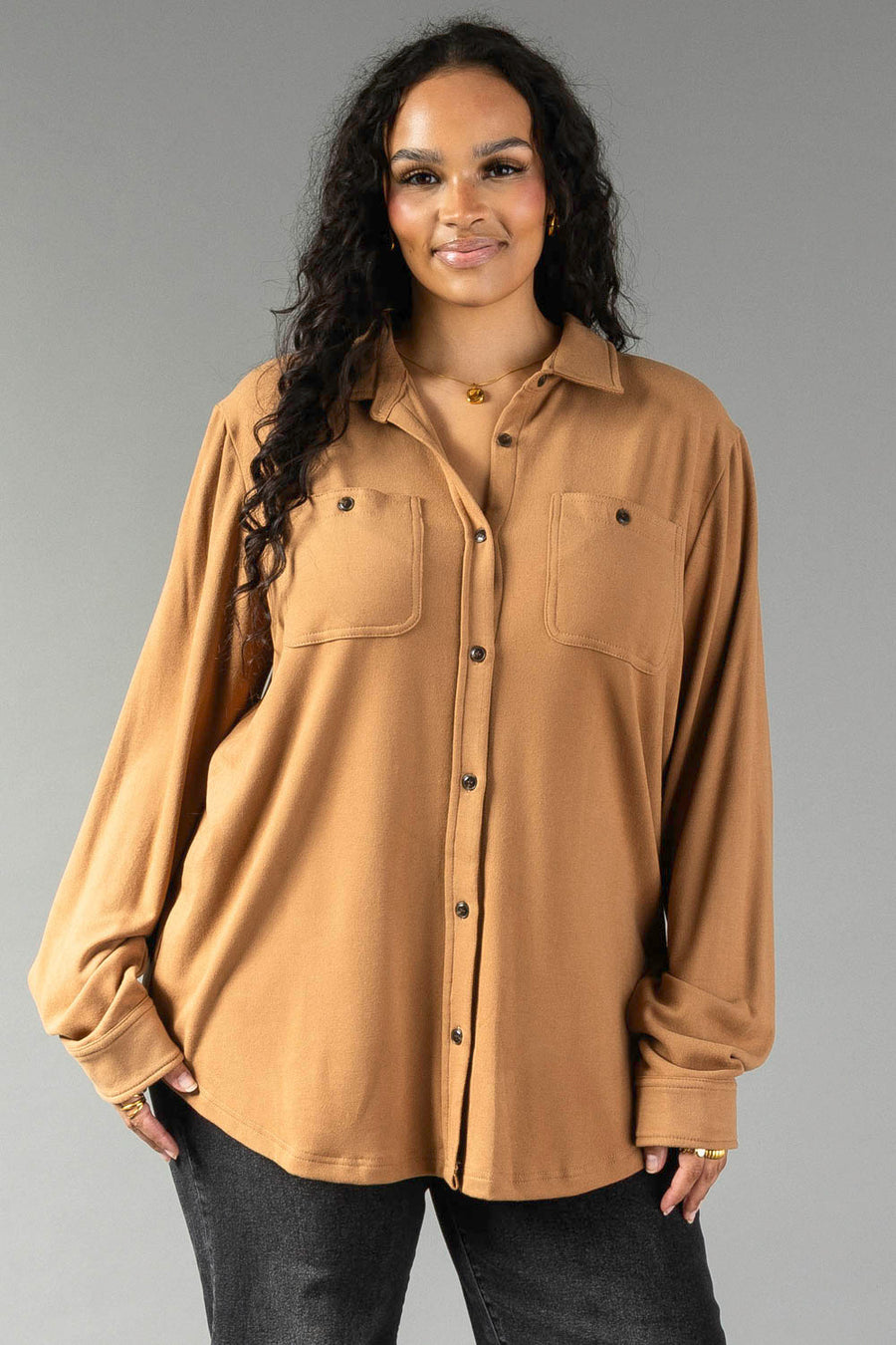 A person wearing a Dark Tan Super Soft Button Up long-sleeved shirt with two chest pockets and dark jeans.