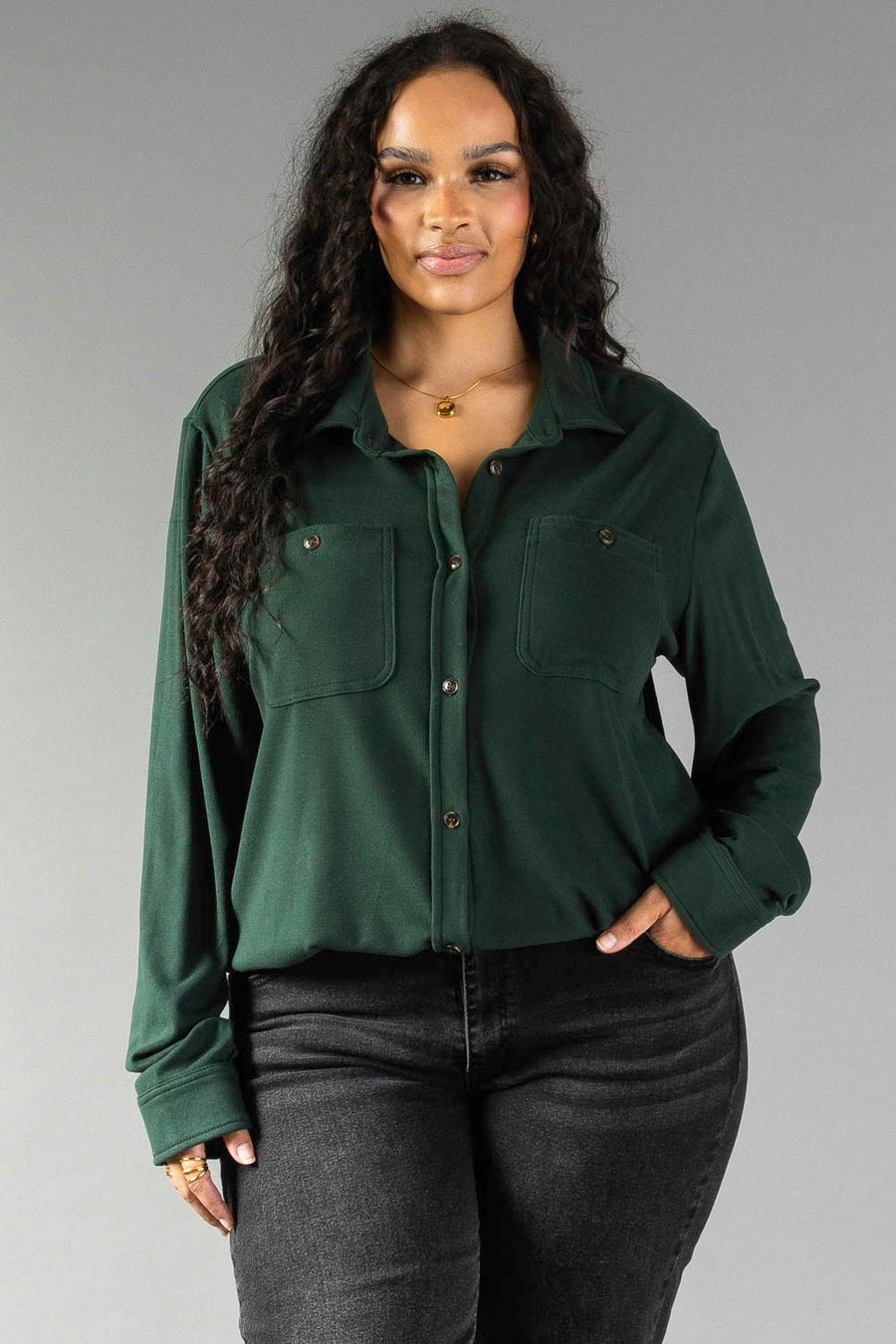 A person wears a hunter green Hunter Green Super Soft Button Up with two chest pockets, paired with dark jeans.