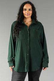A woman wears a Hunter Green Super Soft Button Up, a soft, hunter green long-sleeved shirt with two chest pockets.
