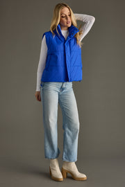 Full-length view of woman wearing Royal Blue quilted puffer vest with high collar and adjustable hem.
