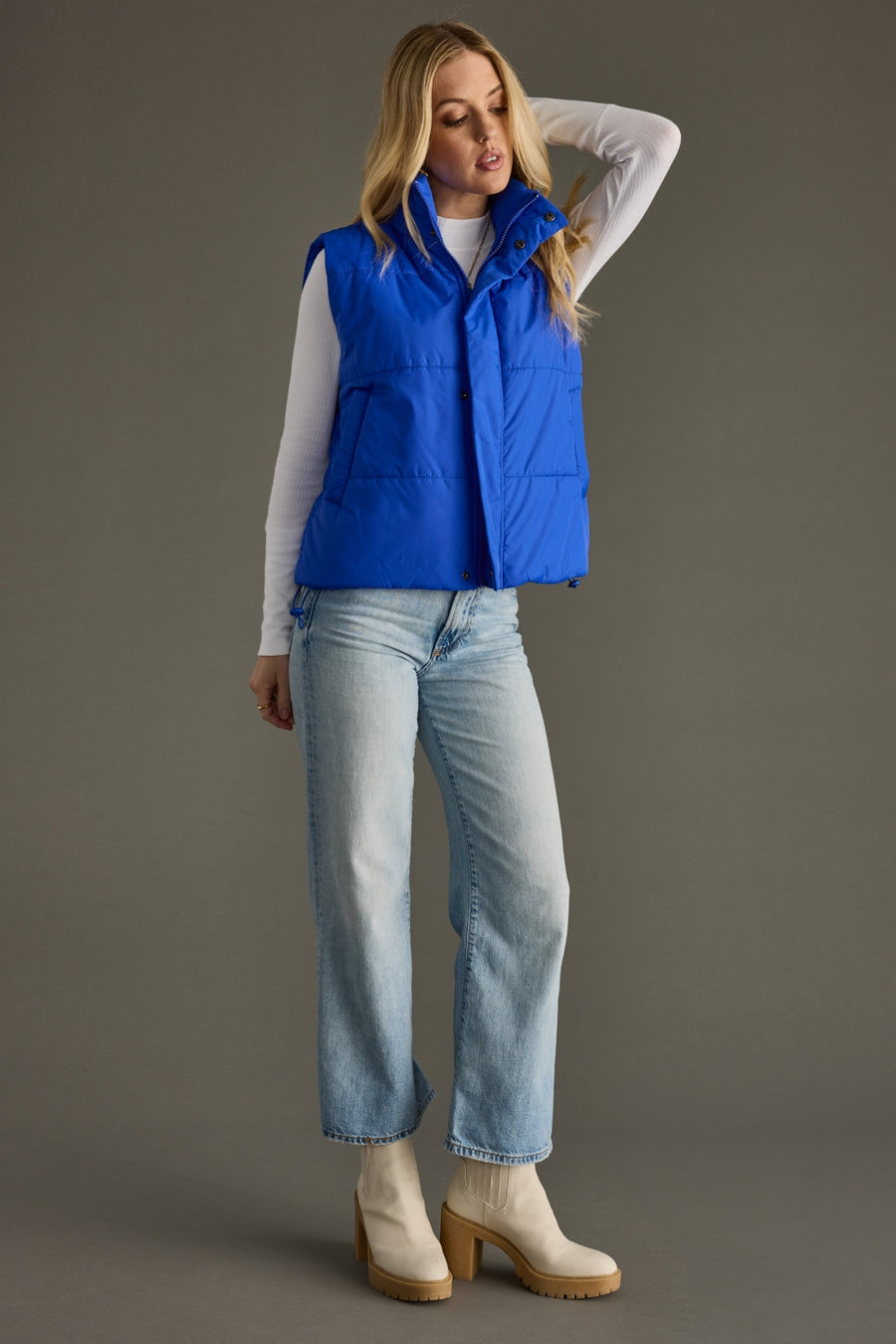 Full-length view of woman wearing Royal Blue quilted puffer vest with high collar and adjustable hem.