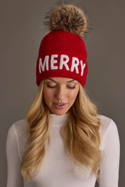 Red Merry Knit Pom Hat featuring the word MERRY in white lettering and a large faux fur pom-pom on top.