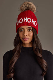A Red Ho Ho Ho Knit Pom Hat with HOHOHO in white text and a brown faux fur pom-pom on top.