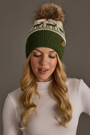 An Olive & Beige Deer Patterned Pom Hat with a green ribbed brim, fleece lining, cream-colored top featuring a green deer pattern, and a large faux fur pom-pom.