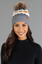 A woman smiles while wearing the Panache Apparel Collection’s Gray with Orange Fox Pattern Knit Pom Hat, styled with a black ribbed long-sleeve top against a plain gray background.