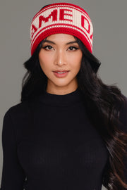 A woman with long, wavy black hair wears the Red & Beige Game Day Knit Headband by Panache Apparel Collection. She has on a black ribbed top and looks directly at the camera with a soft smile.