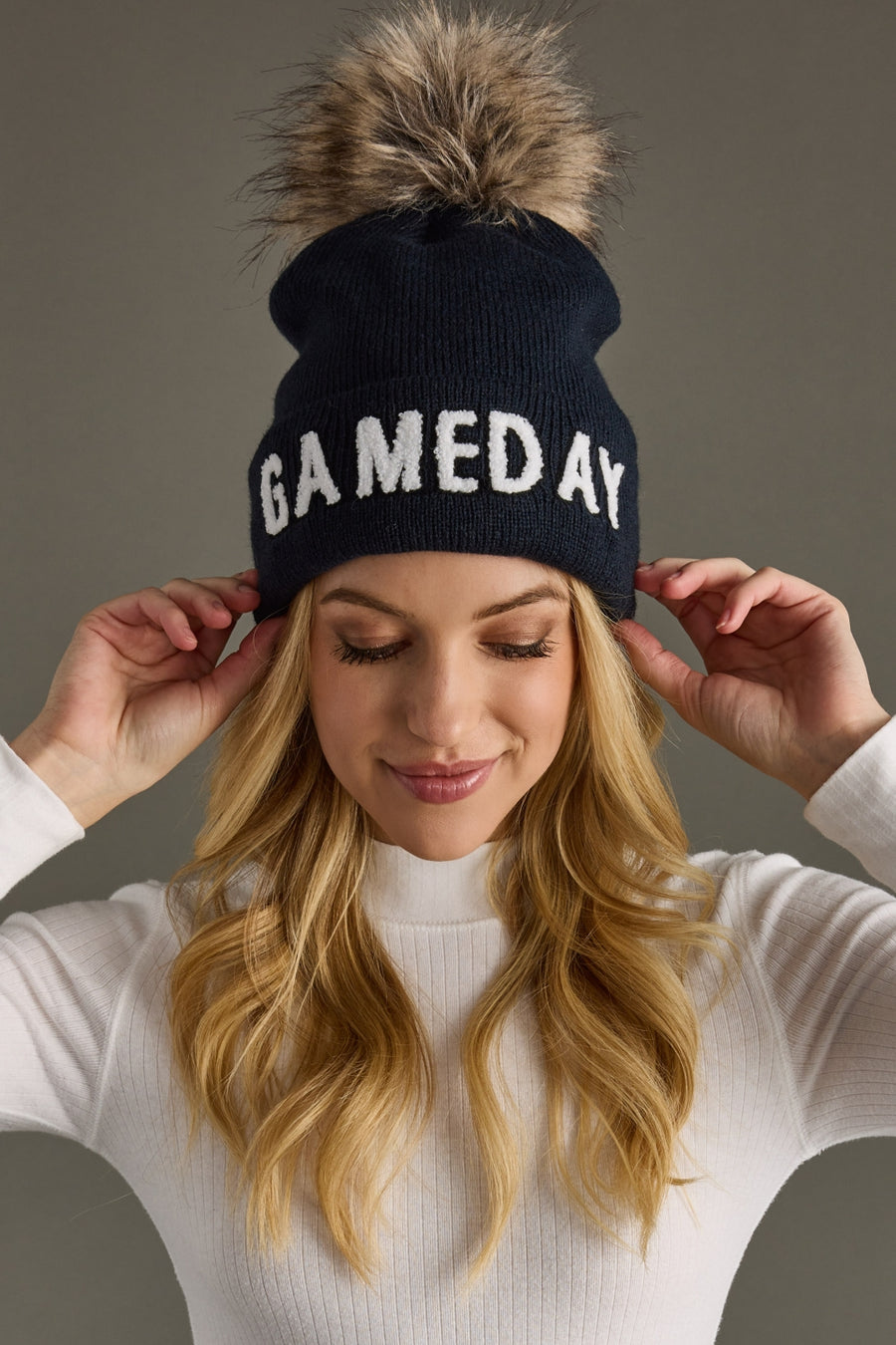 Woman wearing Panache Apparel’s navy and white Game Day pom hat.