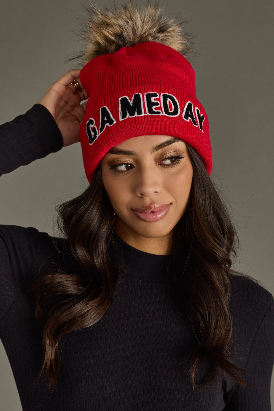 Front view of Panache Apparel’s red and black knit Game Day pom hat on a model.