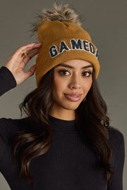 Close-up of woman adjusting Panache Apparel’s camel and gray Game Day pom hat with a soft faux fur topper.