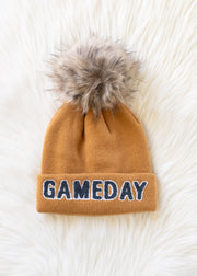Flat lay of Panache Apparel’s camel and gray Game Day knit hat featuring bold text and a faux fur pom.