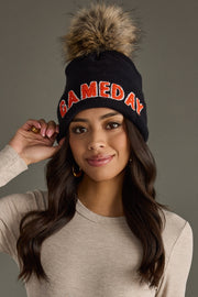 Model wearing Panache Apparel’s black knit Game Day beanie with orange text, ribbed cuff, and faux fur topper.