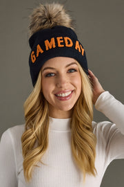 Close-up portrait of a blonde woman wearing Panache Apparel’s navy and orange Game Day pom hat with a faux fur topper.