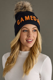 Blonde model showcasing Panache Apparel’s navy Game Day knit beanie with orange lettering and a folded cuff.