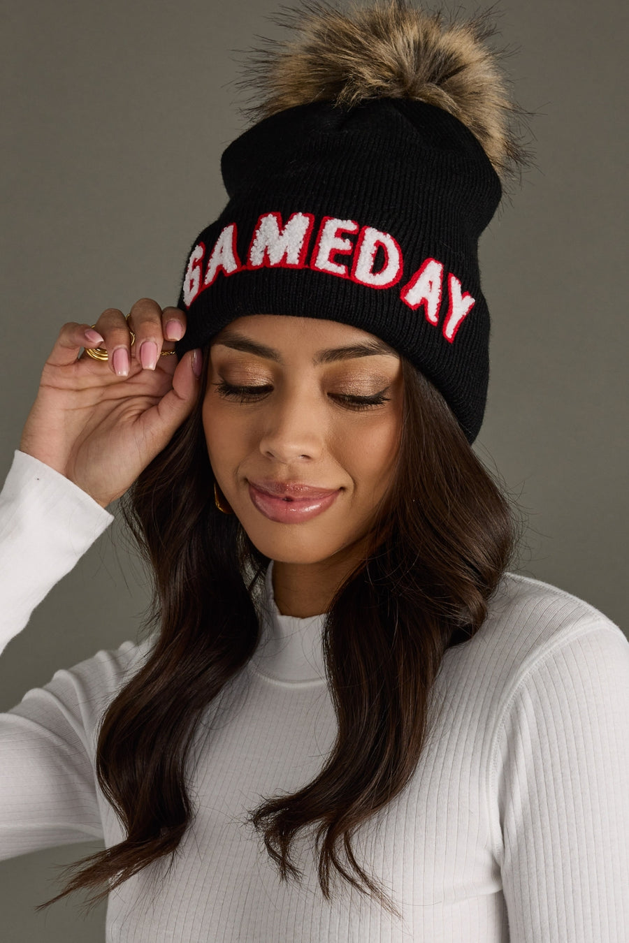 Woman styling Panache Apparel’s black Game Day winter hat featuring contrast white and red text with a folded cuff.
