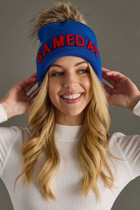 Front portrait of a model styling Panache Apparel’s royal blue Game Day knit hat with red text and a ribbed cuff.