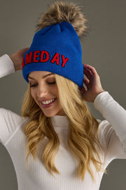 Three-quarter view of a woman wearing Panache Apparel’s royal blue and red Game Day winter hat with a cozy faux fur pom.