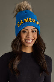 Model showcasing Panache Apparel’s blue and gold Game Day winter hat with a cozy faux fur pom.
