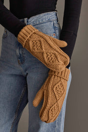 A person wearing blue jeans and a black long-sleeve top is holding the Panache Apparel Collection Khaki Cable Knit Mittens in both hands.