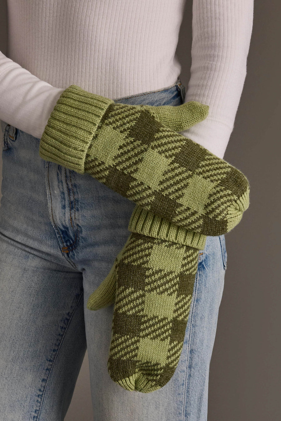 A person wearing light blue jeans, a white ribbed long-sleeve shirt, and the Panache Apparel Collection Light Green & Olive Plaid Knit Mittens, standing against a neutral background.