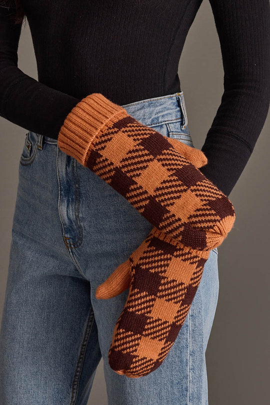A person wearing high-waisted blue jeans, a black long-sleeve top, and Panache Apparel Collection’s Orange & Brown Plaid Knit Mittens, standing against a neutral background.