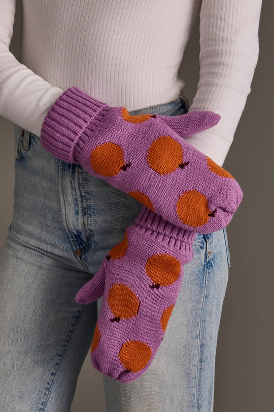 A person in a white ribbed shirt and blue jeans wears the Panache Apparel Collection Orange Pattern Knit Mittens.