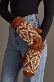 A person wearing high-waisted blue jeans, a black long-sleeve top, and Panache Apparel Collection Camel & Beige Patterned Knit Mittens is standing against a plain gray background. Only the torso and hands are visible.