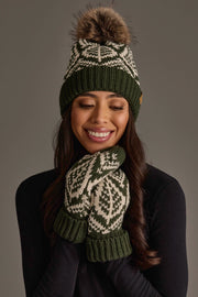 A woman wearing the Olive & Beige Patterned Knit Pom Hat from Panache Apparel Collection and matching green and white mittens smiles with her hands near her face against a neutral background.