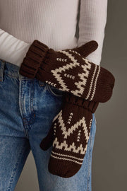 A person wearing blue jeans and a white ribbed long-sleeve top is holding their hands together while wearing the Panache Apparel Collection Chocolate Brown & Beige Patterned Mittens.