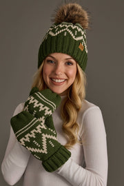 A smiling woman in a white top wears the Olive & Beige Patterned Pom Hat by Panache Apparel Collection, along with matching mittens featuring white patterns, as she poses against a plain gray background.