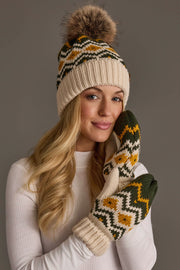 A woman in a cream sweater wears the Panache Apparel Collection Cream, Olive & Mustard Patterned Pom Hat with matching mittens, smiling softly against a gray background.