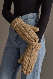 A person wearing a black ribbed long-sleeve top, blue jeans, and the Panache Apparel Collection Tan Cable Knit Design Mittens stands with arms crossed.