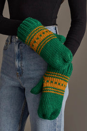 A person wearing blue jeans, a black long-sleeve top, and Panache Apparel Collection’s Green & Gold Patterned Knit Mittens stands against a neutral background.
