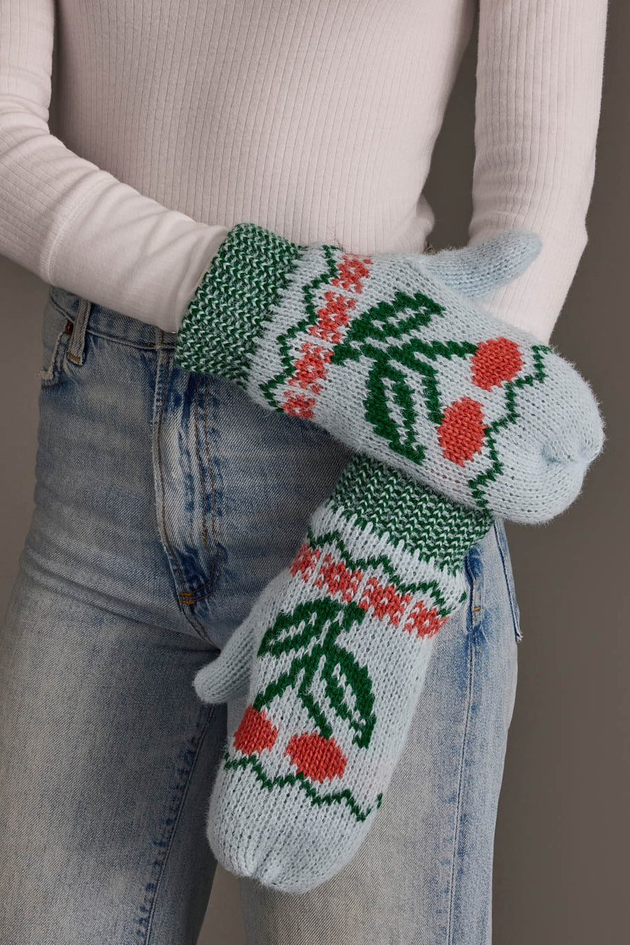 A person wearing Panache Apparel Collection’s Light Blue Cherry Pattern Mittens, paired with a white ribbed top and light blue jeans.