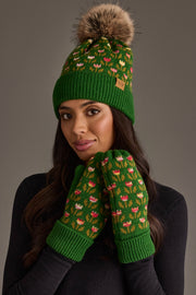 A woman models the Panache Apparel Collection’s Green Small Floral Pattern Knit Pom Hat, featuring a brown faux fur pom-pom, along with matching green mittens adorned with a colorful heart pattern, against a plain gray background.