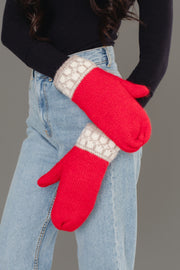 A person in light blue jeans and a black top crosses their arms against a gray background, wearing Panache Apparel Collection’s Red & Taupe Patterned Knit Mittens.
