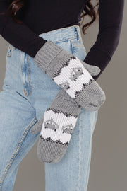 A person wearing light blue jeans and a black long-sleeve shirt, with their arms crossed, displays the Panache Apparel Collection’s Gray with Gray Fox Pattern Knit Mittens.