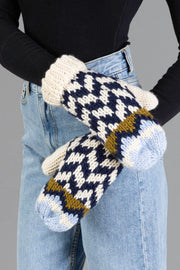 A person wearing light blue jeans and a black long-sleeve top shows off the Beige, Navy & Light Blue Patterned Mittens from Panache Apparel Collection.