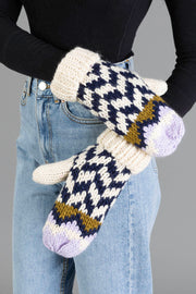 A person wearing light blue jeans, a black top, and a pair of Panache Apparel Collection Beige, Navy & Lilac Patterned Mittens.