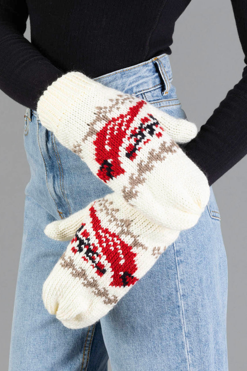 A person wearing high-waisted blue jeans and a black top showcases the Ivory Cardinal Pattern Mittens by Panache Apparel Collection, cream-colored knit mittens featuring red and black cardinal designs on the back of each hand.