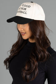 A woman with long brown hair, dressed in a black top, stands against a plain gray background wearing the Panache Apparel Collection’s "It's A Good Day For Football" Two-Toned Trucker Hat.