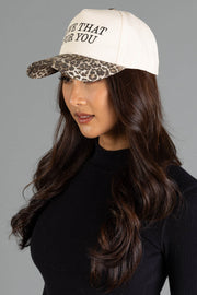 A person wears a Love That For You Ivory & Leopard Two-Toned Trucker Hat, featuring an ivory crown, leopard print brim, and the text LOVE THAT FOR YOU on the front.