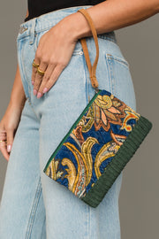 Woman carrying Panache Apparel Collection’s green and multicolored patterned wristlet with tan strap and textured trim.